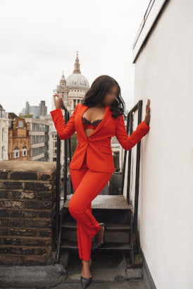 Black girl in a striking red suit with a backdrop of a cathedral
